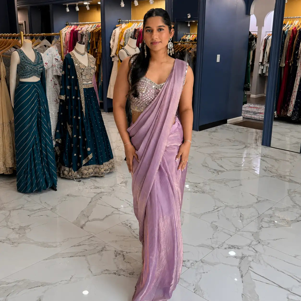 A woman wearing a lavender silk saree with subtle shimmering details.